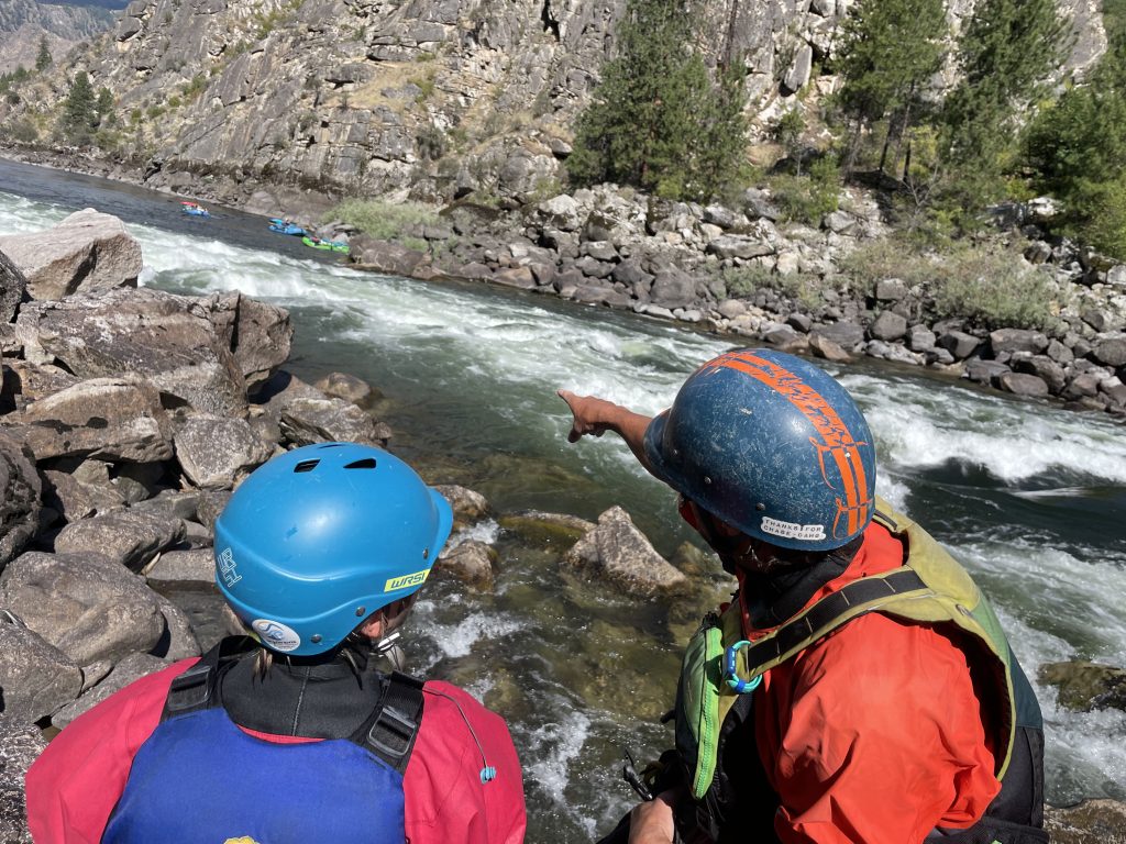 Teen learning rapid scouting techniques with a river guide in Idaho.
