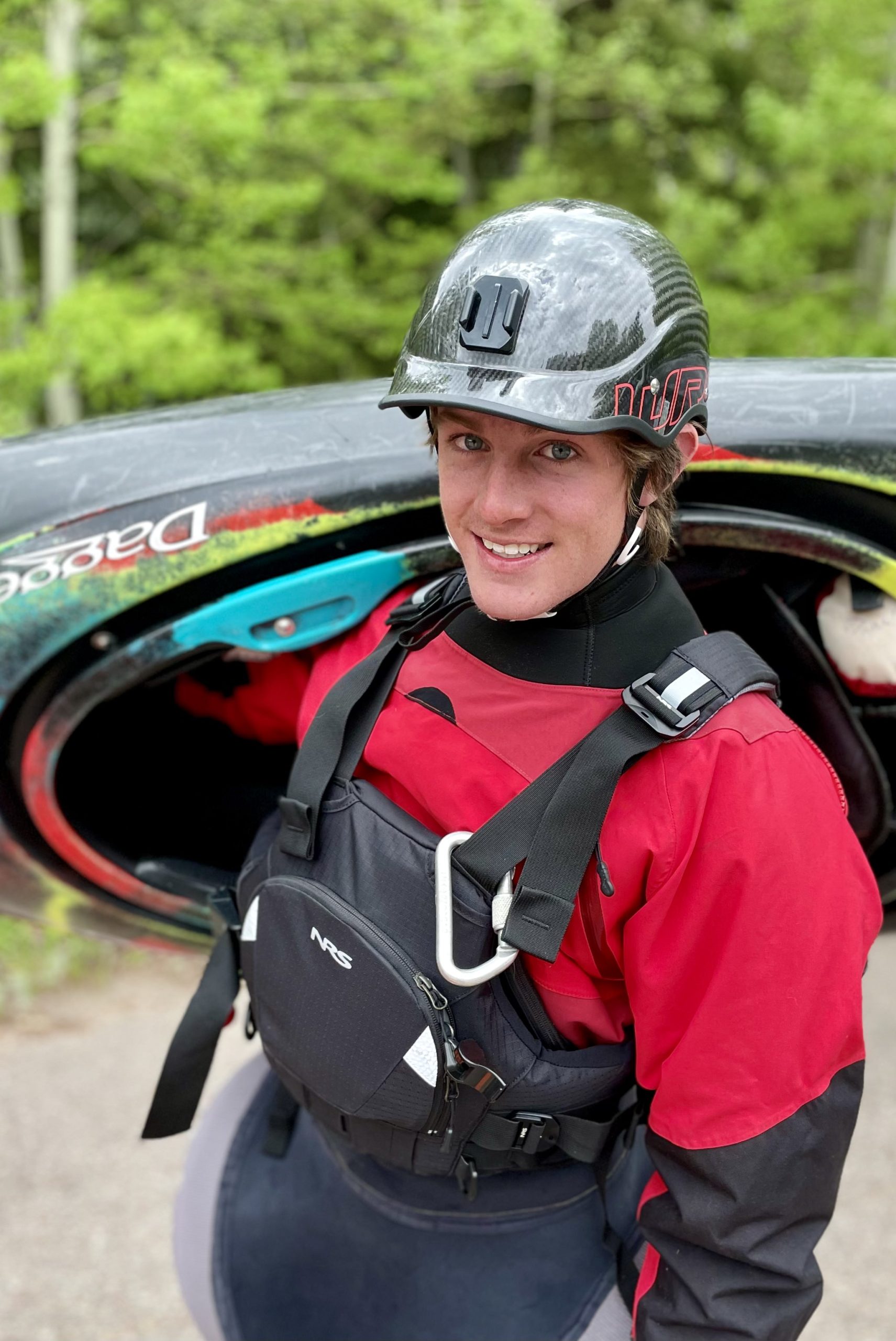Outdoor adventure guide with helmet and kayak by the Idaho river.