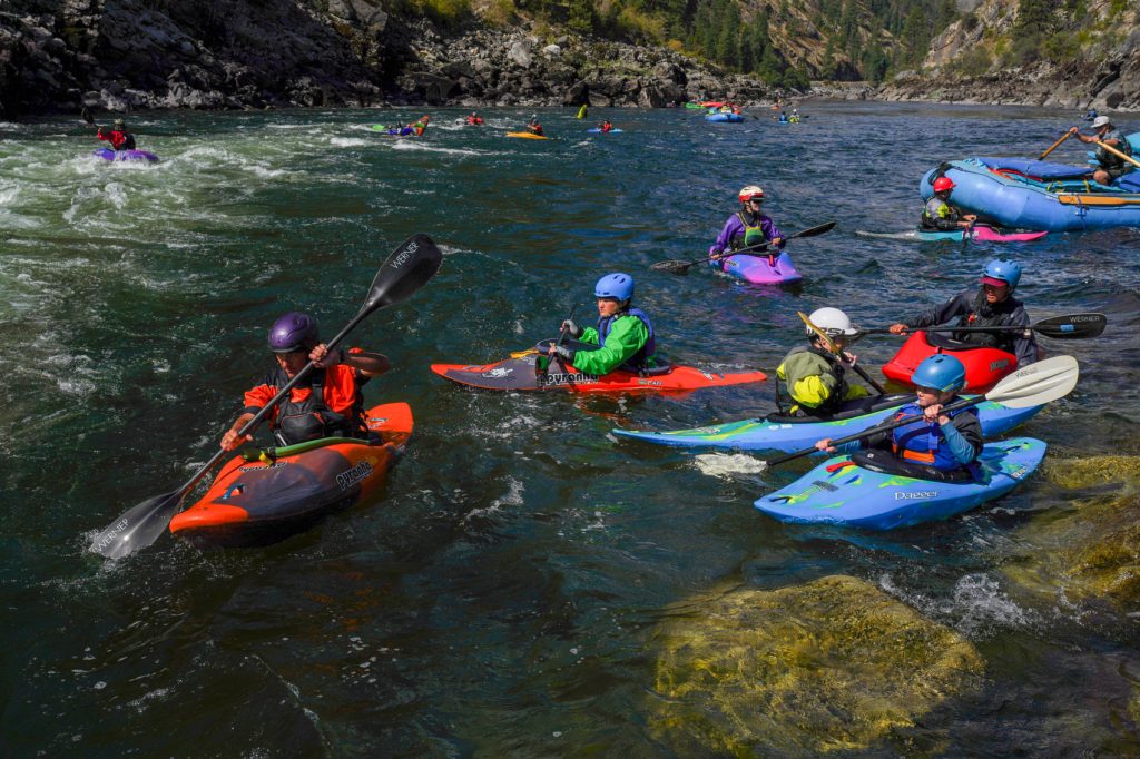 Kayakers paddling as a group through calm river water.