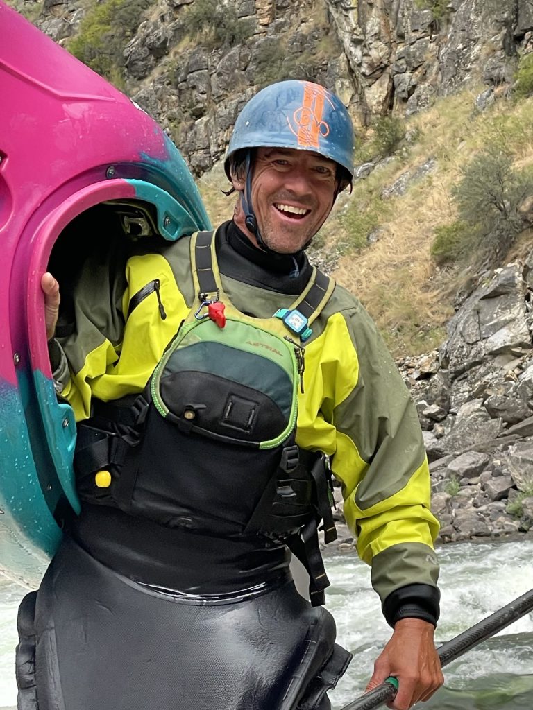 Tommy Hilleke, owner and guide, smiling while holding a kayak on the Salmon River.
